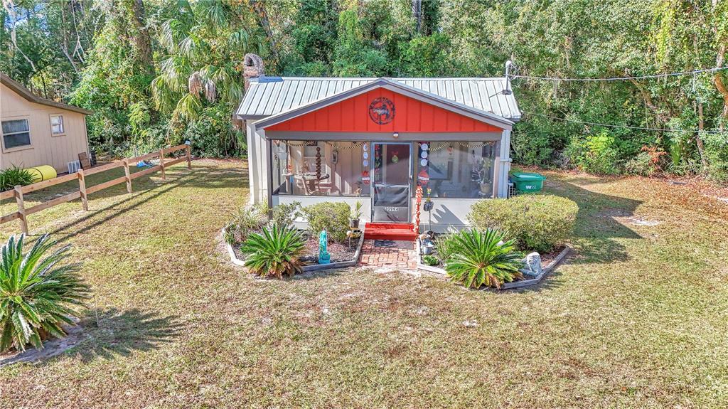 A small house with a metal roof and a screened-in front porch sits on grass — 20990 W PENNSYLVANIA AVENUE, DUNNELLON, FL