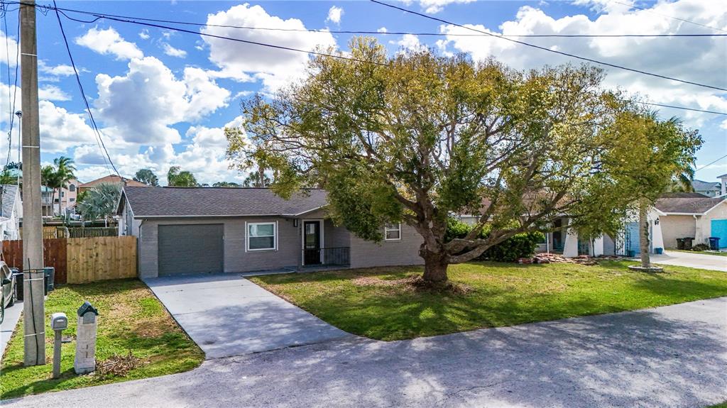 A single-story gray brick house with a garage and a large tree in the yard — 7434 MAKO DRIVE, HUDSON, FL