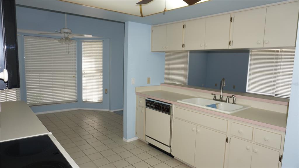 A kitchen with white cabinets, a dishwasher, a double sink, and a tiled floor — 10512 TAPESTRY DRIVE, PORT RICHEY, FL