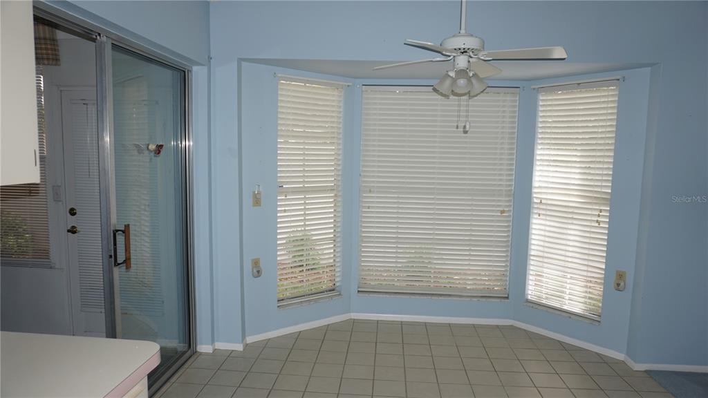 A breakfast nook with light blue walls, tile flooring, a ceiling fan, and bay windows — 10512 TAPESTRY DRIVE, PORT RICHEY, FL
