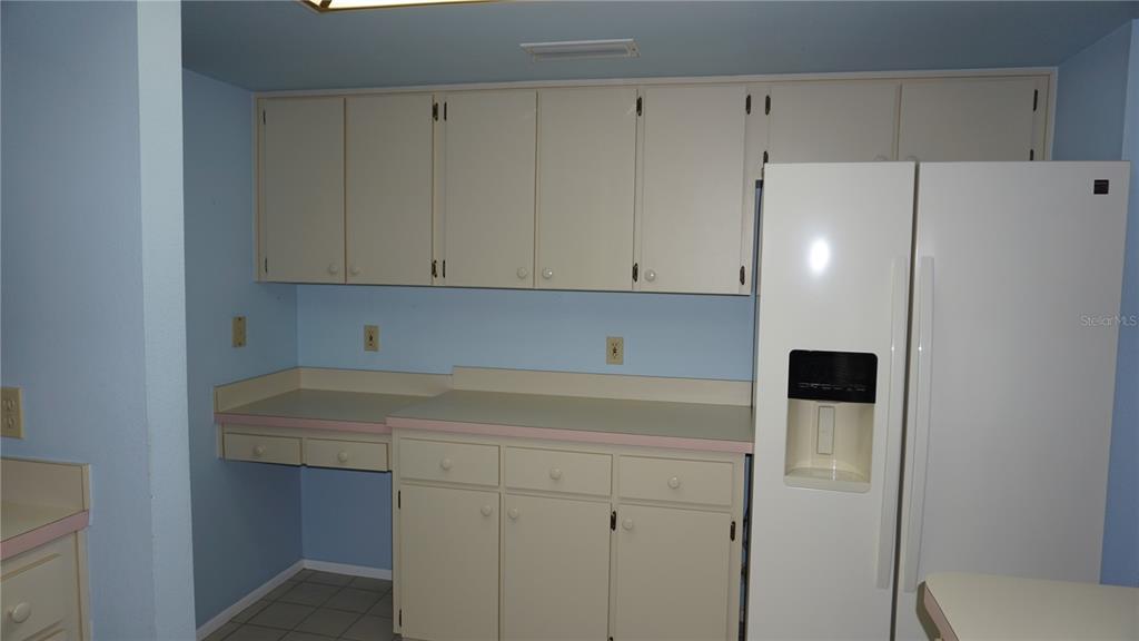 A kitchen features light blue walls, off-white cabinets, a white refrigerator, and laminate countertops — 10512 TAPESTRY DRIVE, PORT RICHEY, FL