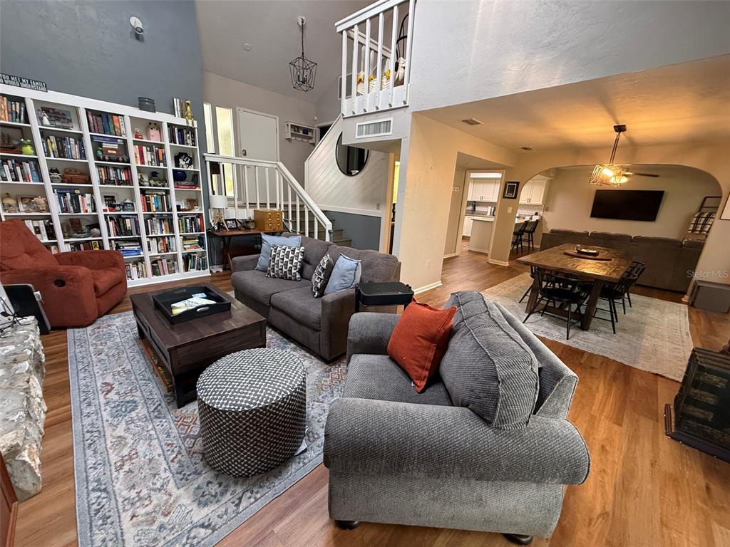 A living room features a stone fireplace, vaulted ceilings, hardwood floors, and an orange armchair — 1629 NW 19TH CIRCLE, GAINESVILLE, FL