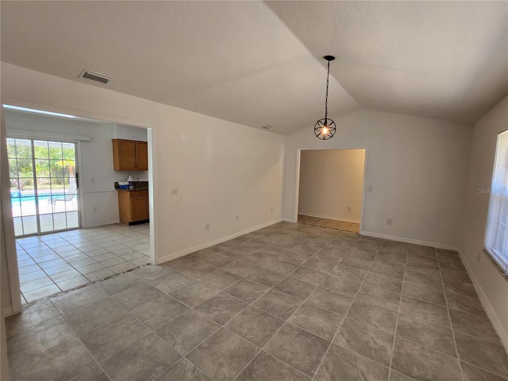 A tiled living room with a vaulted ceiling and a view into the kitchen — 9 TEAK WAY DRIVE, OCALA, FL