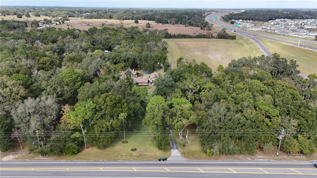 An aerial view shows a house nestled in a wooded lot near a highway — 3525 W KELLY PARK ROAD, APOPKA, FL