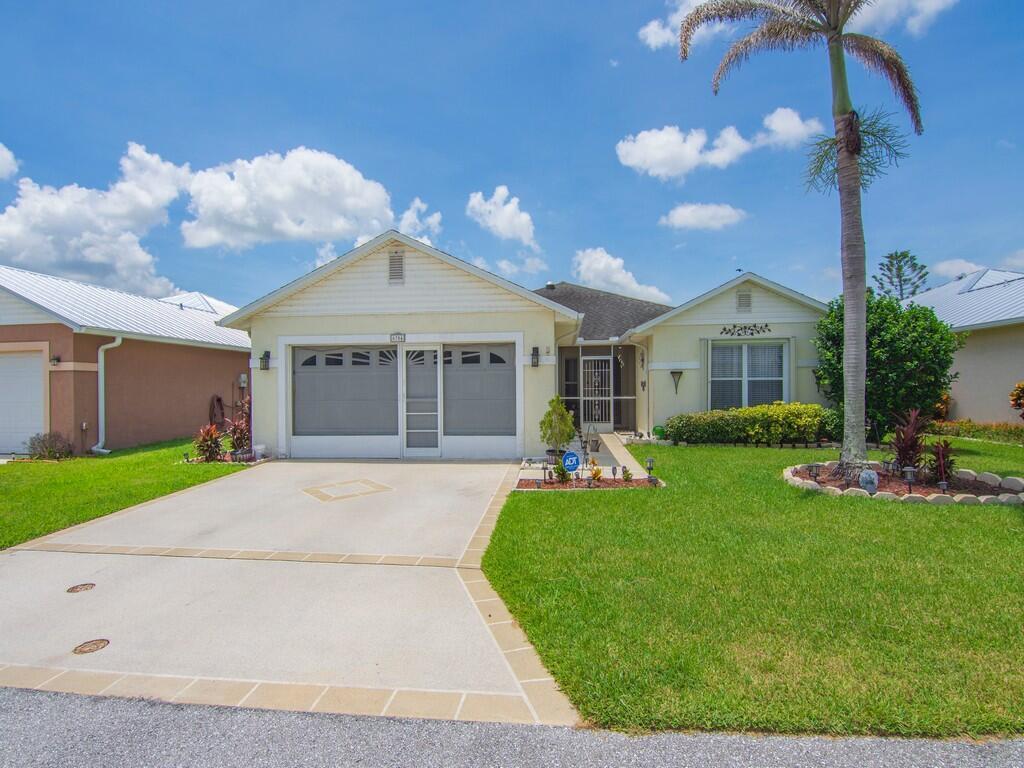 A single-story house with a two-car garage, a palm tree, and a green lawn — 6704 Picante Circle, Fort Pierce FL 34951, FORT PIERCE, FL