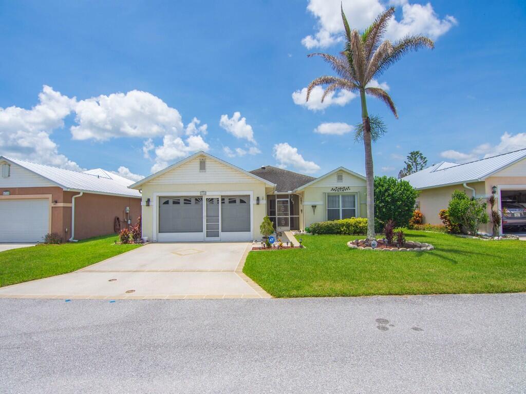 A single-story house with a light yellow exterior, a two-car garage, and a palm tree — 6704 Picante Circle, Fort Pierce FL 34951, FORT PIERCE, FL