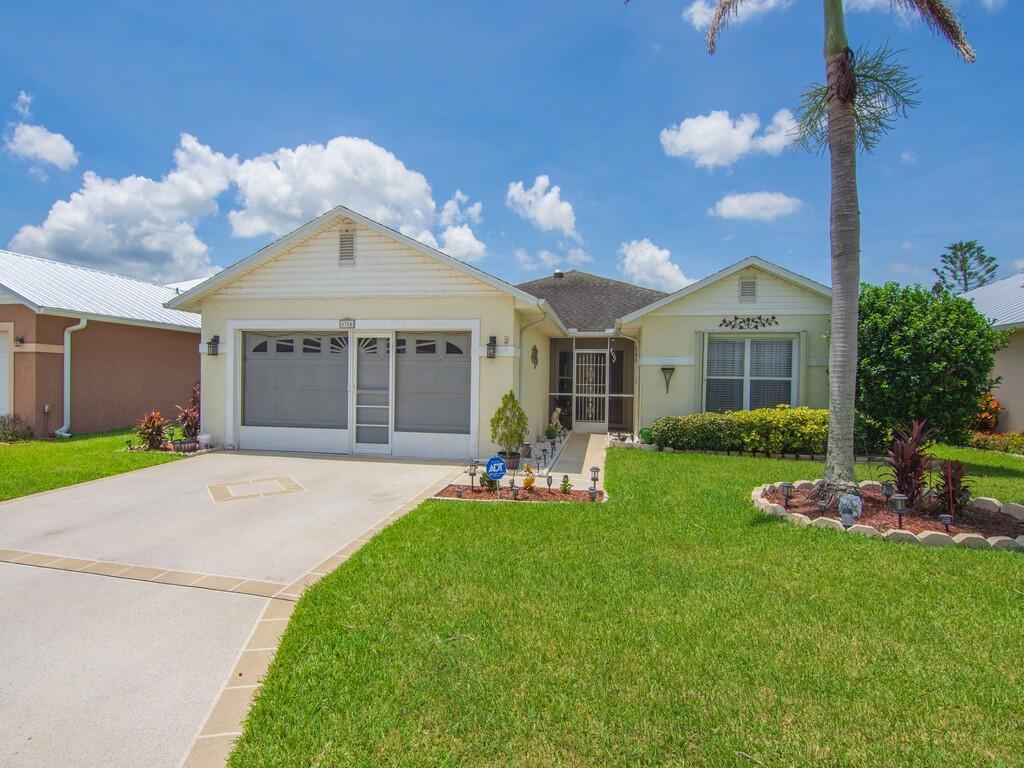 A single-story house with a garage, a palm tree, and a green lawn under blue skies — 6704 Picante Circle, Fort Pierce FL 34951, FORT PIERCE, FL