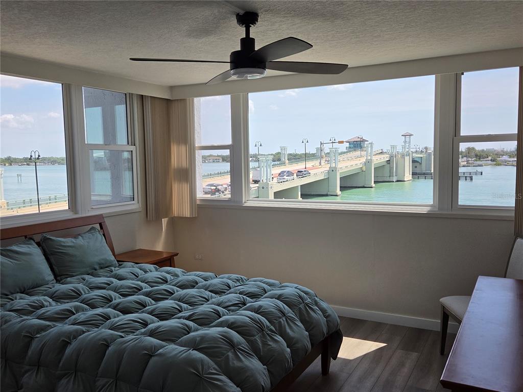 A bedroom with a bed and ceiling fan overlooks a bridge spanning a body of water — 500 TREASURE ISLAND CAUSEWAY UNIT 307, TREASURE ISLAND, FL