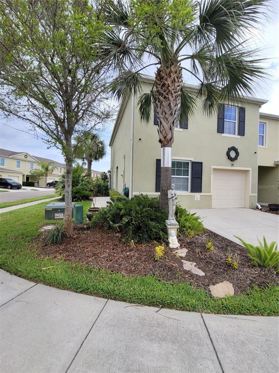 A two-story light green house features a palm tree and a statue in the front yard — 273 ARBOR LAKES DRIVE, DAVENPORT, FL
