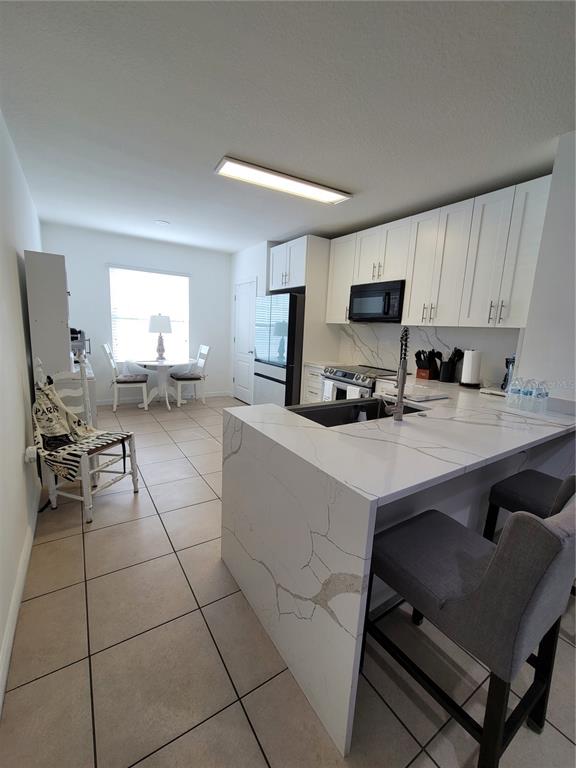 A kitchen with white cabinets, marble-look countertops, and a breakfast nook with a table — 273 ARBOR LAKES DRIVE, DAVENPORT, FL