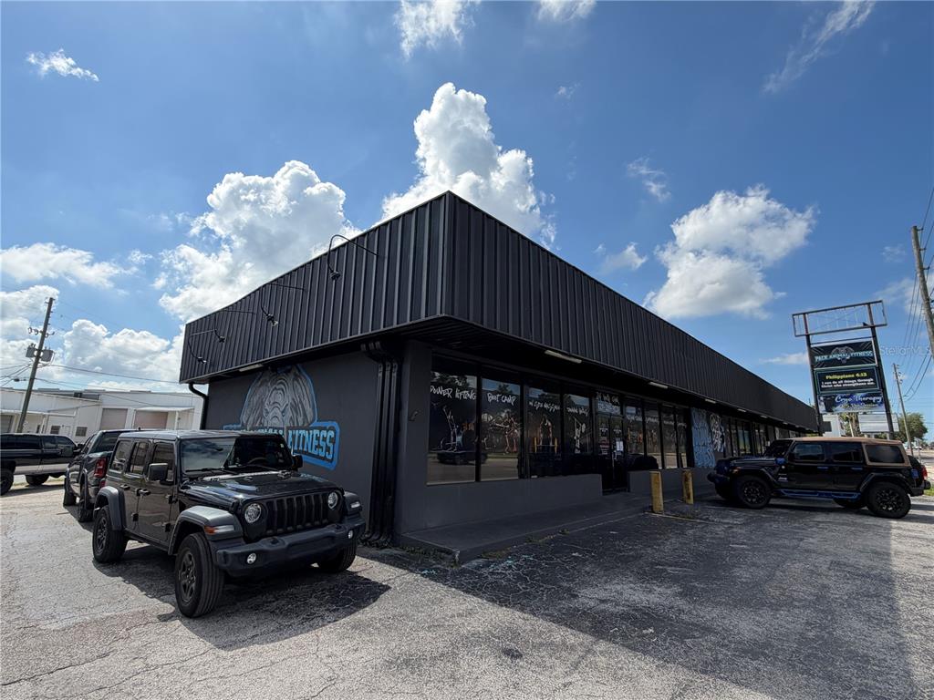 A black-painted commercial building features large windows and a parking lot with two Jeeps — 5983 49TH STREET N, ST PETERSBURG, FL