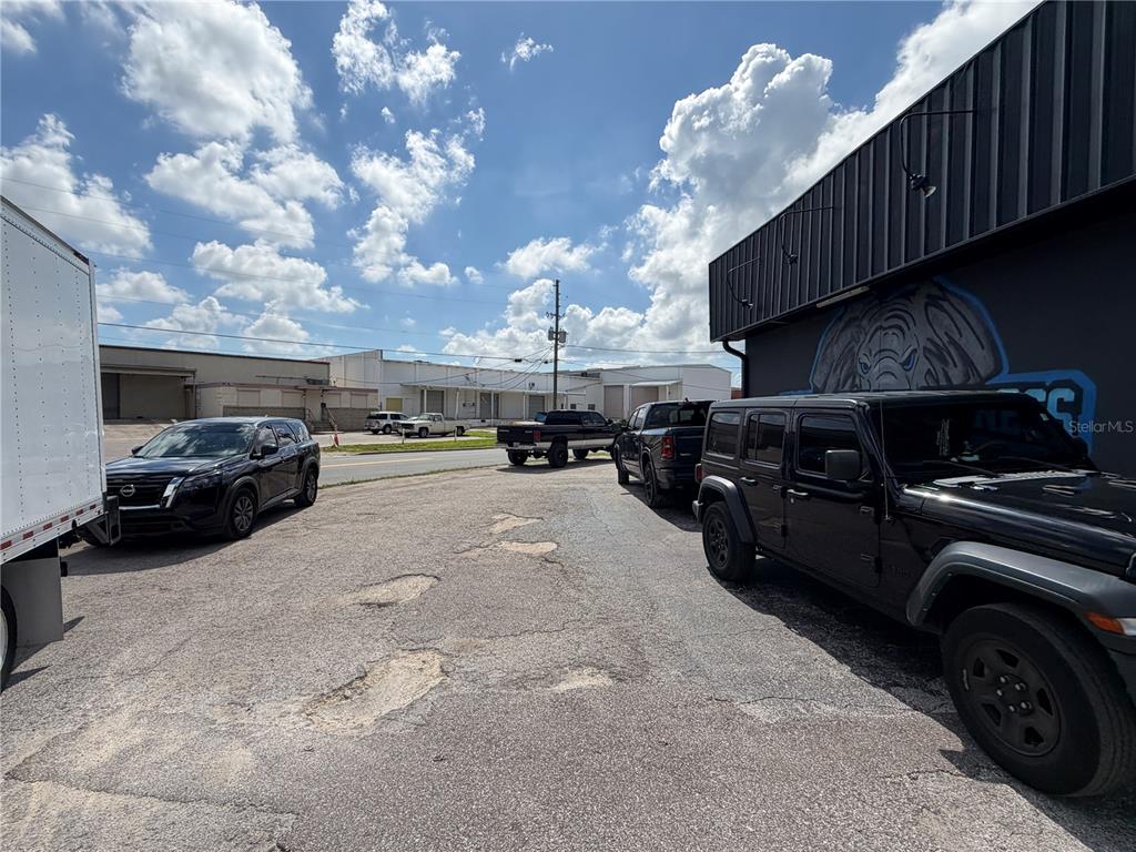 A gravel parking lot sits between a commercial building and a street with parked vehicles — 5983 49TH STREET N, ST PETERSBURG, FL
