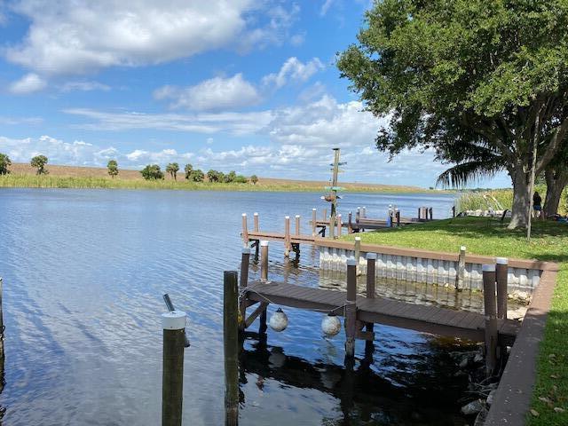 A wooden dock extends into a calm lake under a blue sky with scattered clouds — 8680 Us Highway 441 # B3, Okeechobee FL 34974, OKEECHOBEE, FL