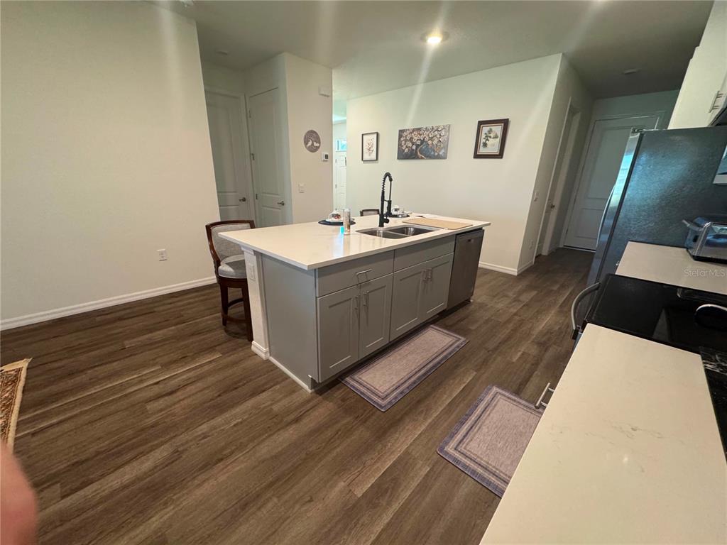 A kitchen features a central island with a sink, gray cabinetry, and wood-look flooring — 2615 KINSALE LANE, ORMOND BEACH, FL