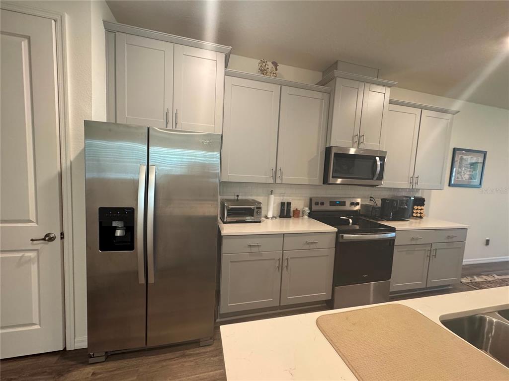 A kitchen features gray shaker cabinets, stainless steel appliances, and white countertops — 2615 KINSALE LANE, ORMOND BEACH, FL