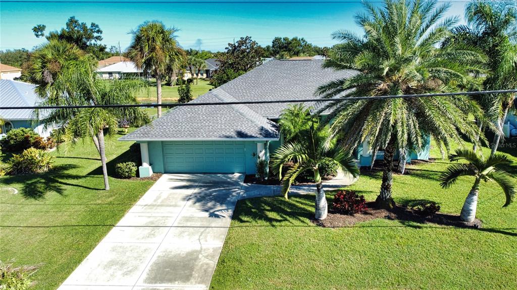 An aerial view of a single-story house with a blue garage and palm trees — 525 ROTONDA CIRCLE, ROTONDA WEST, FL