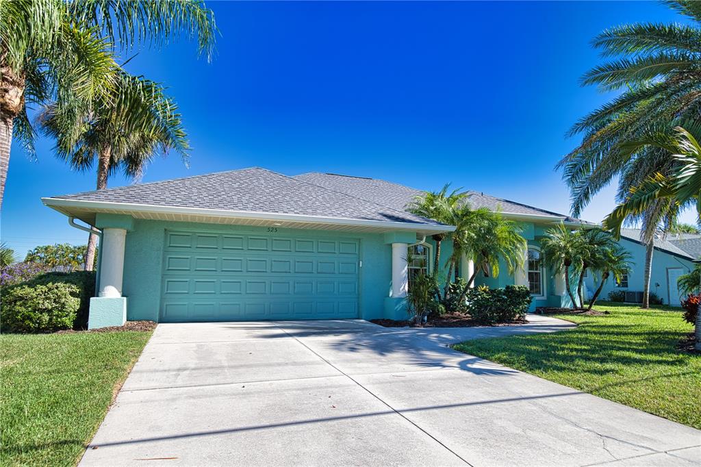 A teal single-story house with a two-car garage and palm trees under a clear sky — 525 ROTONDA CIRCLE, ROTONDA WEST, FL