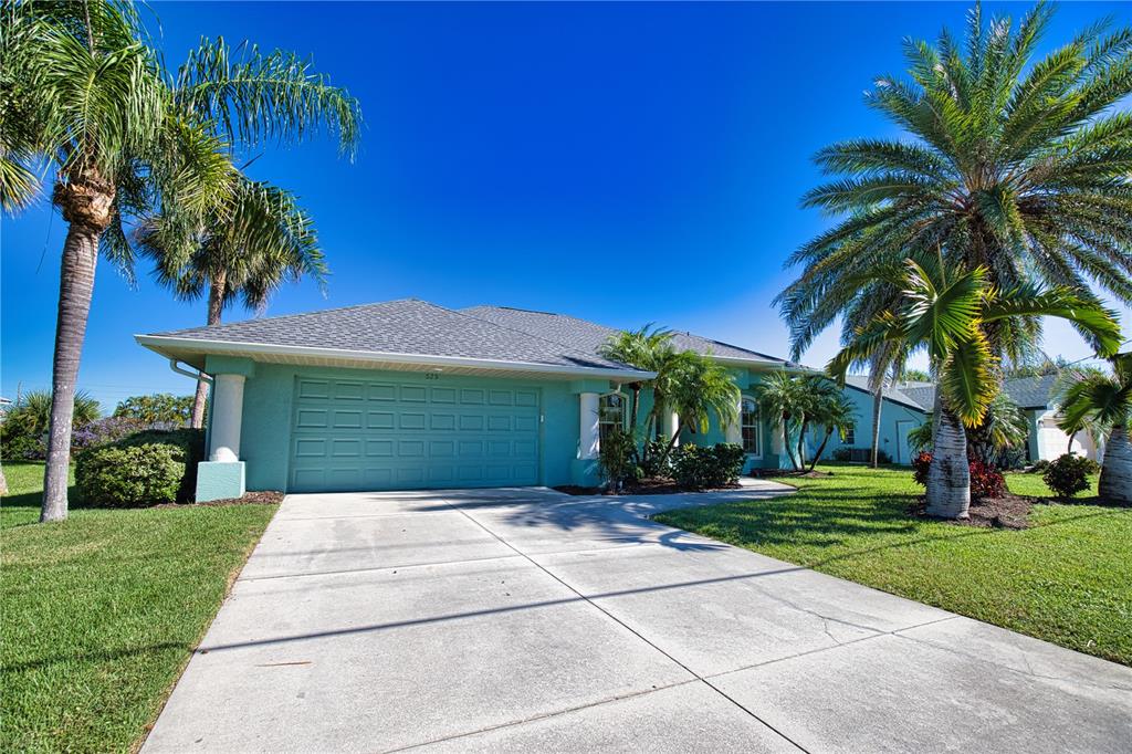 A teal single-story house with a two-car garage and palm trees in the front yard — 525 ROTONDA CIRCLE, ROTONDA WEST, FL