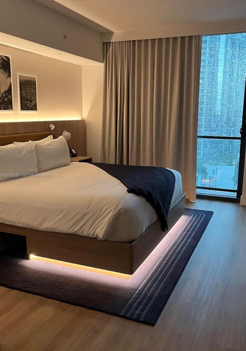 A modern bedroom features a platform bed with under-lighting, a dark rug, and floor-to-ceiling windows — 601 NE 1st Ave # 1720, Miami FL 33132, MIAMI, FL