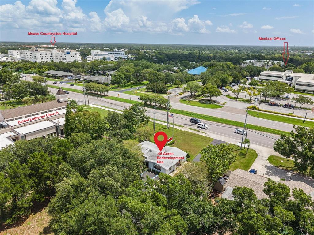An aerial view shows a small building on a wooded lot near a busy road — 3150 N MCMULLEN BOOTH ROAD, CLEARWATER, FL