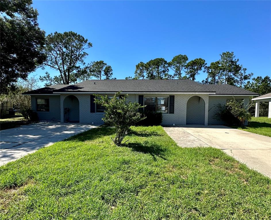 A single-story duplex with gray brick siding, two arched entryways, and two concrete driveways — 544 IMPERIAL PLACE, KISSIMMEE, FL