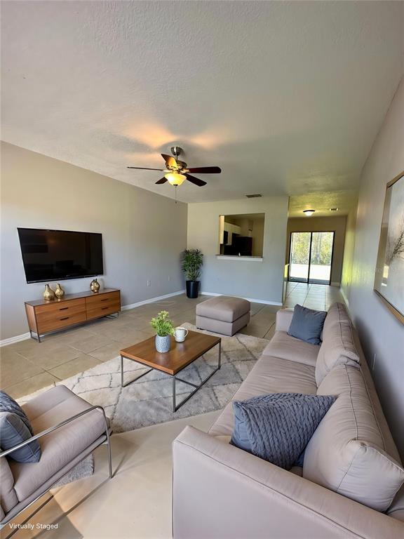 A living room features tile flooring, a ceiling fan, a television, and a neutral sofa — 544 IMPERIAL PLACE, KISSIMMEE, FL