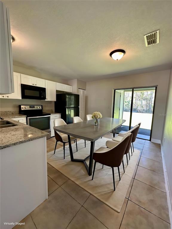 A kitchen and dining area features white cabinets, granite countertops, and a modern dining table — 544 IMPERIAL PLACE, KISSIMMEE, FL
