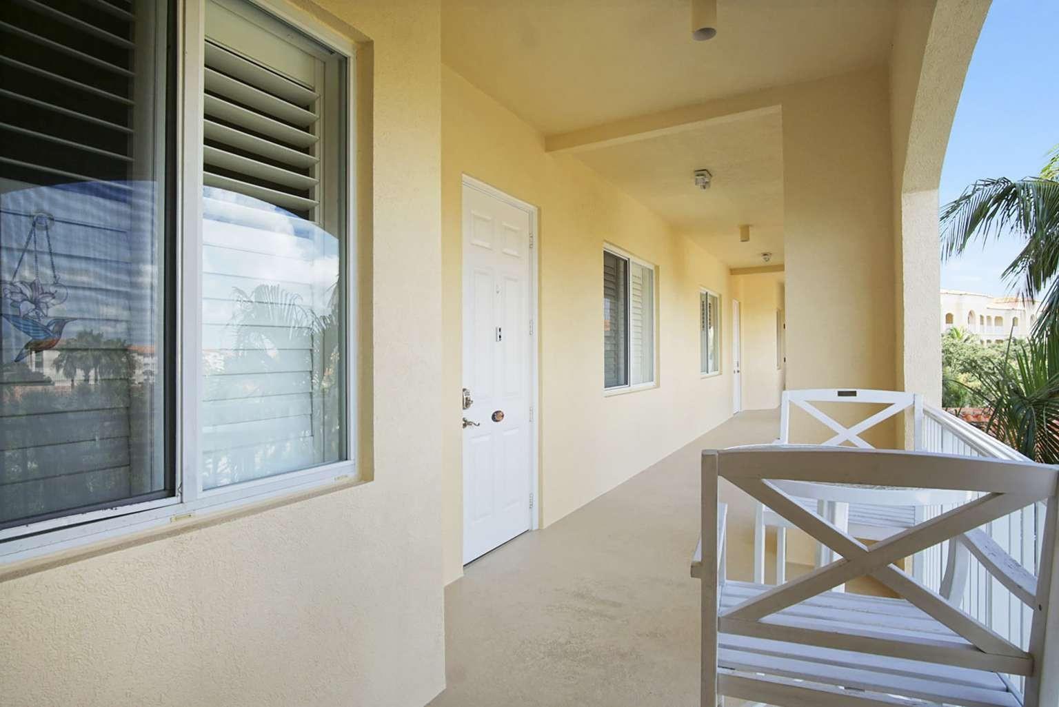 A covered outdoor balcony features a white door, windows, and a small table with chairs — 3 Harbour Isle Drive # 302, Fort Pierce FL 34949, FORT PIERCE, FL