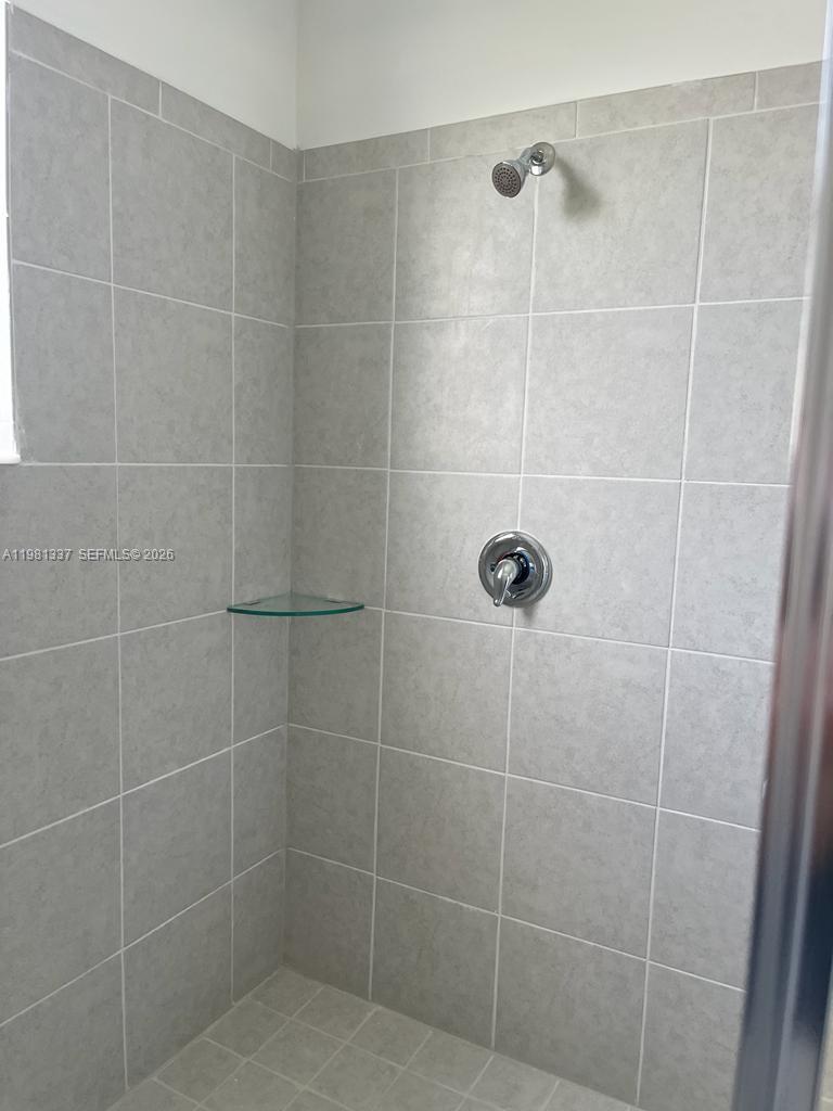 A tiled walk-in shower features a glass corner shelf and a chrome shower head — 14806 SW 163rd St, Miami FL 33187, MIAMI, FL