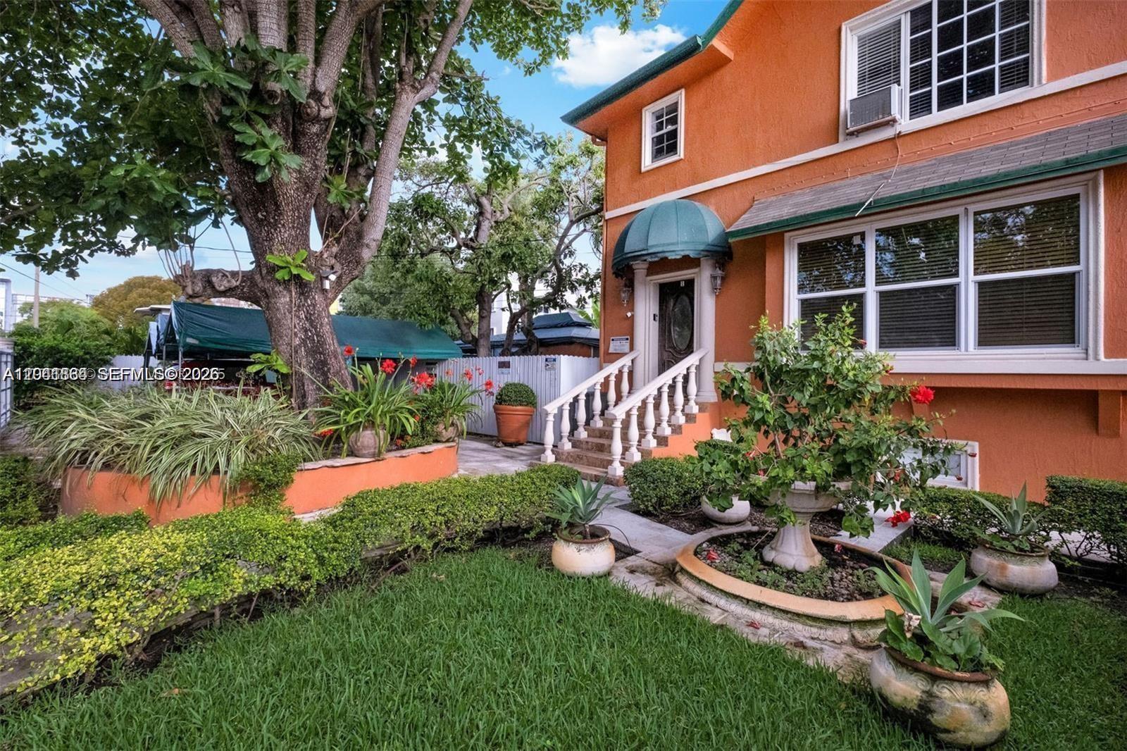 An orange two-story house features a front porch with white railings and landscaping — 1033 NW 6th St Unit 1, Miami FL 33136, MIAMI, FL
