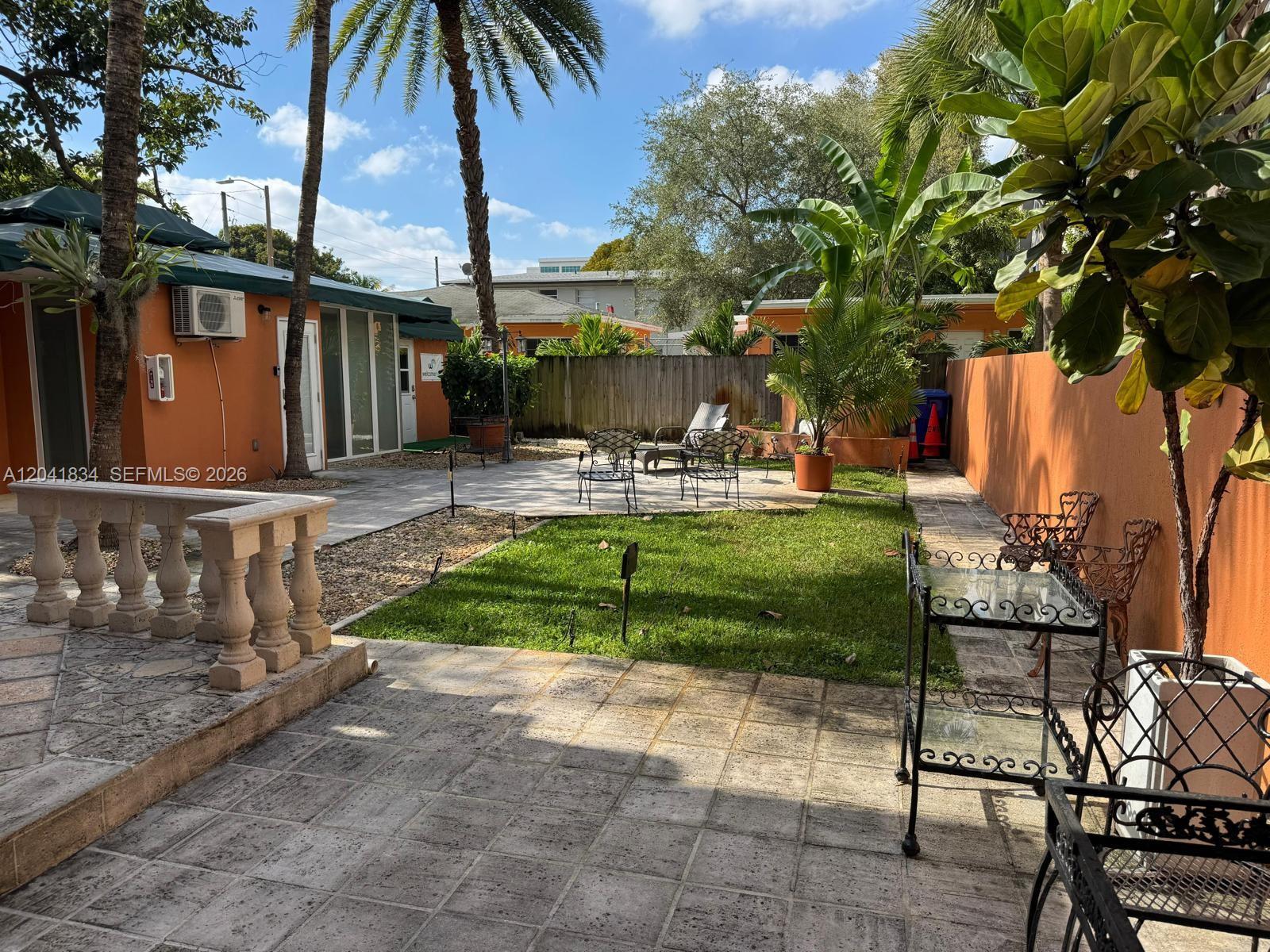 A backyard features a paved patio, a small grass lawn, palm trees, and outdoor furniture — 1033 NW 6th St Unit 1, Miami FL 33136, MIAMI, FL
