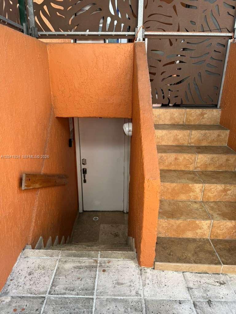 A white door is located at the bottom of a short outdoor concrete staircase — 1033 NW 6th St Unit 1, Miami FL 33136, MIAMI, FL