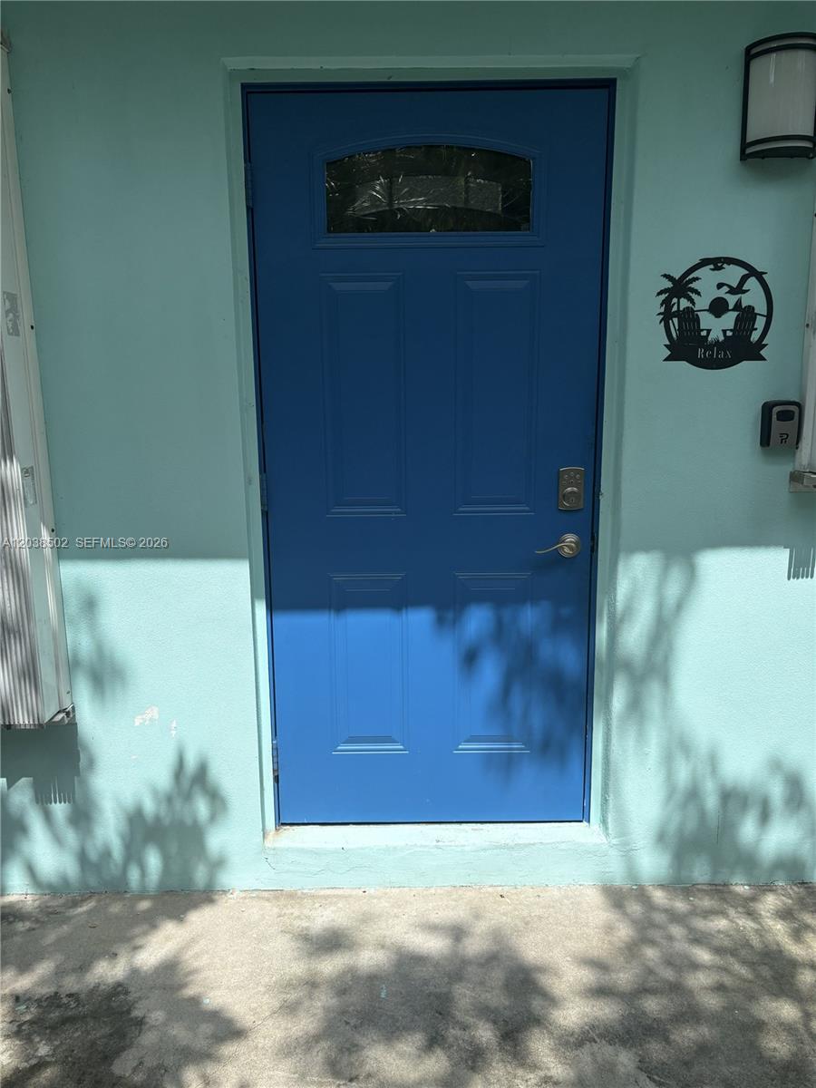 A bright blue front door is set into a light green exterior wall — 8 Jewfish Ave, Key Largo FL 33037, KEY LARGO, FL