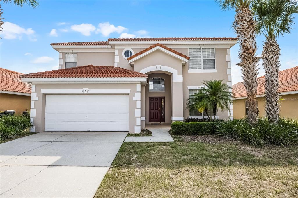 A two-story house with a beige stucco exterior, a red tile roof, and a garage — 321 ROSSO DRIVE, DAVENPORT, FL
