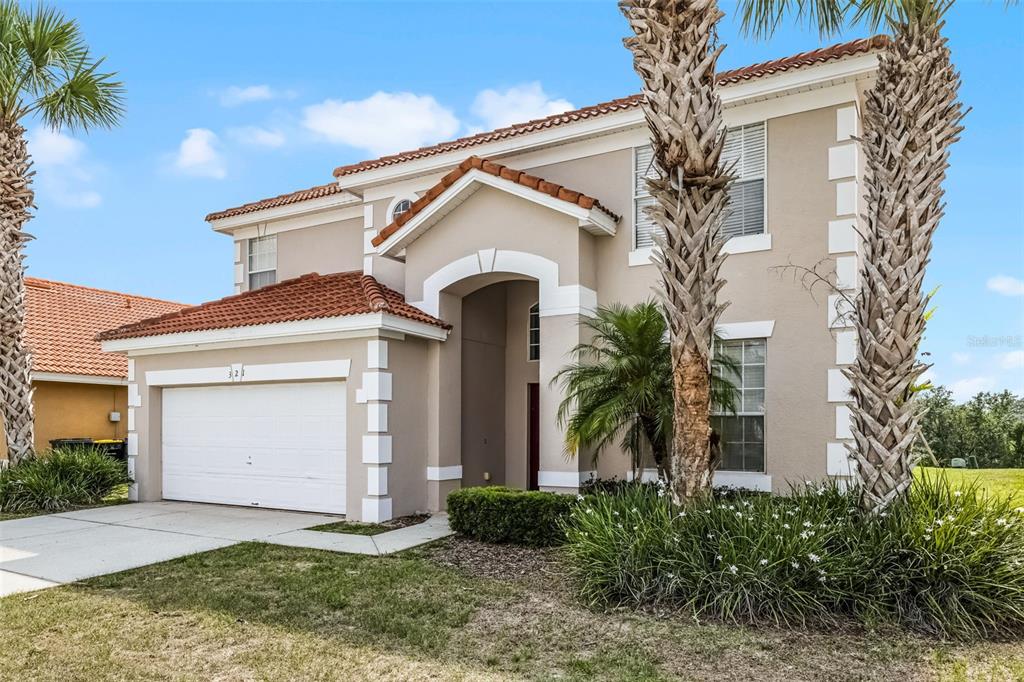 A two-story house with a beige stucco exterior, white trim, and a red tile roof — 321 ROSSO DRIVE, DAVENPORT, FL