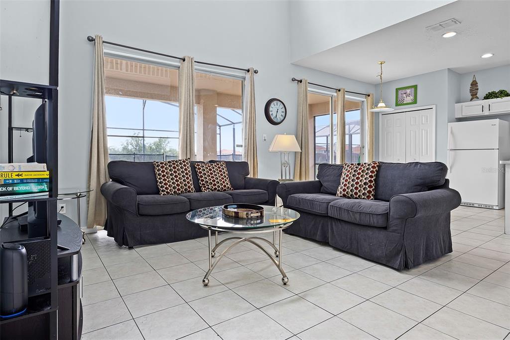 A living room features two dark sofas, a glass coffee table, and tiled flooring — 321 ROSSO DRIVE, DAVENPORT, FL