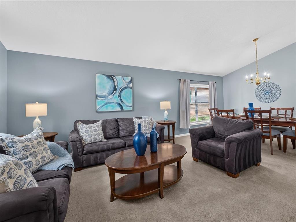 A living room with gray walls, dark furniture, a coffee table, and an adjacent dining area — 554 PALOMA DRIVE, DAVENPORT, FL