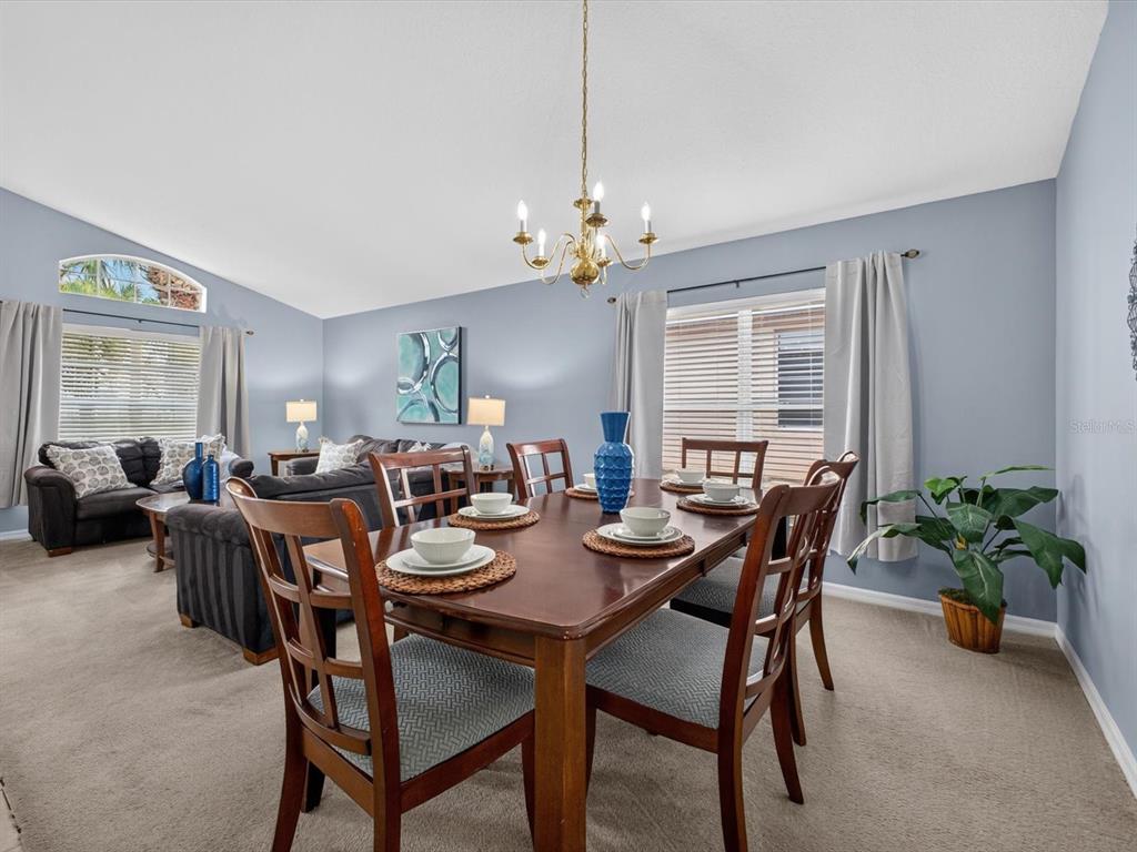 A dining area with a wooden table and chairs sits in front of a living room — 554 PALOMA DRIVE, DAVENPORT, FL