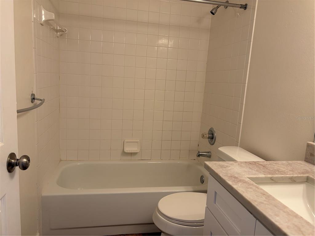 A bathroom features a white tiled shower-tub combination, a toilet, and a vanity with countertop — 11516 WHISPERING HOLLOW DRIVE, TAMPA, FL