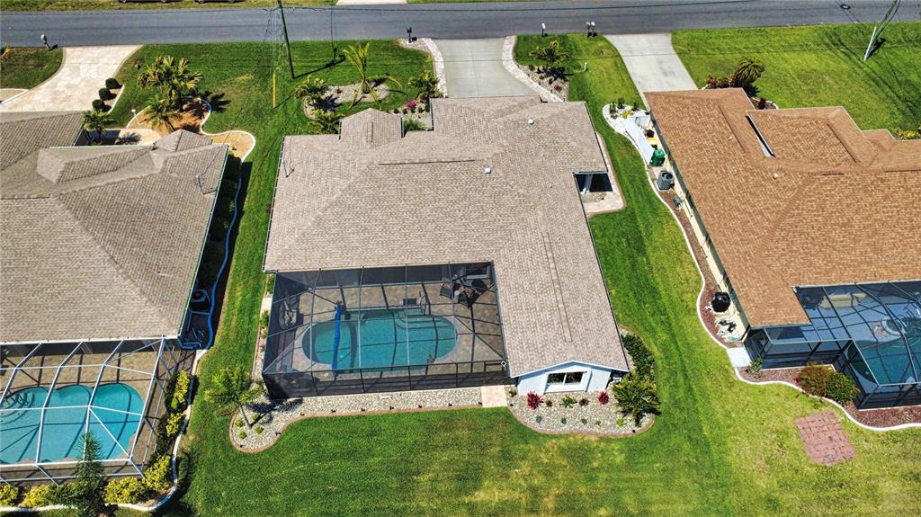 An aerial view of a suburban house with a screened-in pool and a shingled roof — 22 MEDALIST COURT, ROTONDA WEST, FL