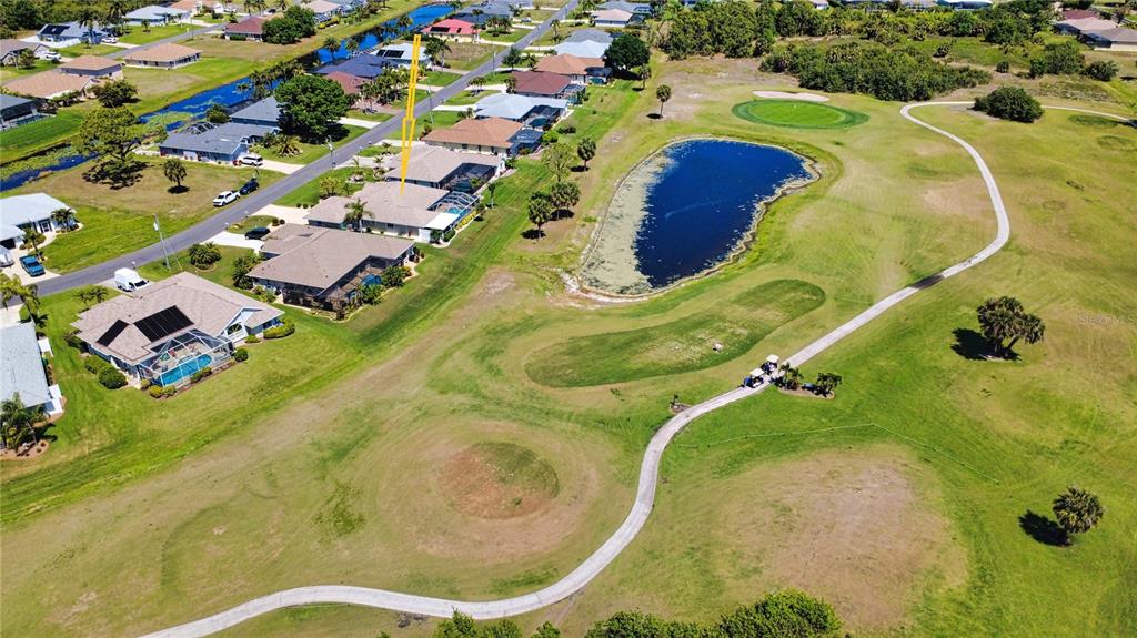 An aerial view shows a residential house with a pool overlooking a golf course pond — 22 MEDALIST COURT, ROTONDA WEST, FL