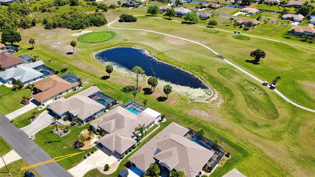 An aerial view shows suburban houses with swimming pools bordering a golf course and pond — 22 MEDALIST COURT, ROTONDA WEST, FL