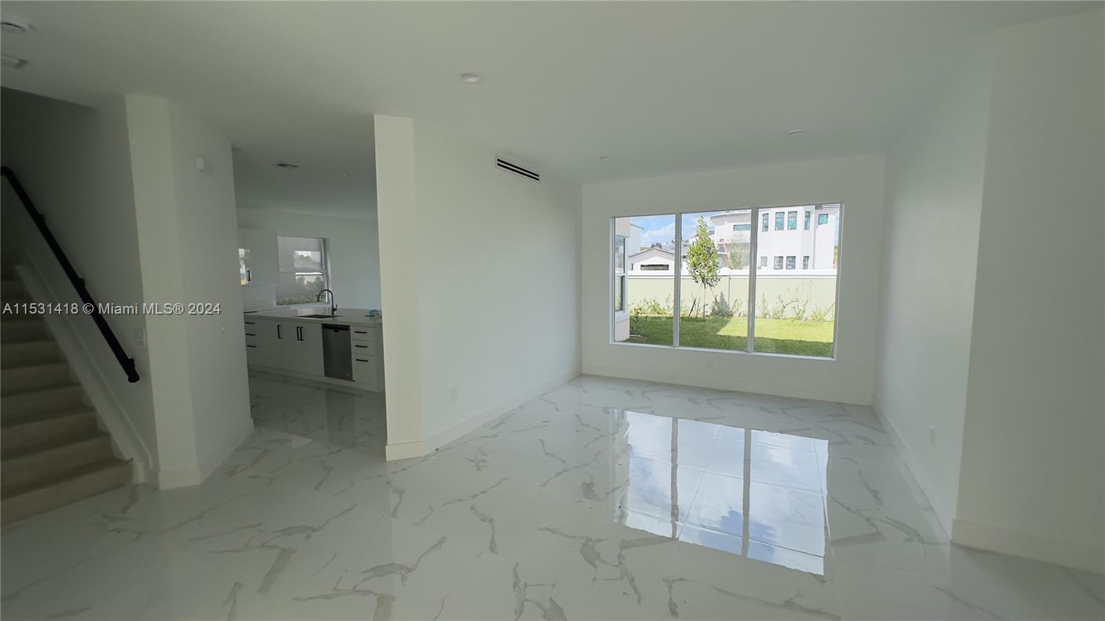 A bright living area features white marble-look tile flooring and a view of the backyard — 3523 Forest View Cir, Dania Beach FL 33312, DANIA BEACH, FL