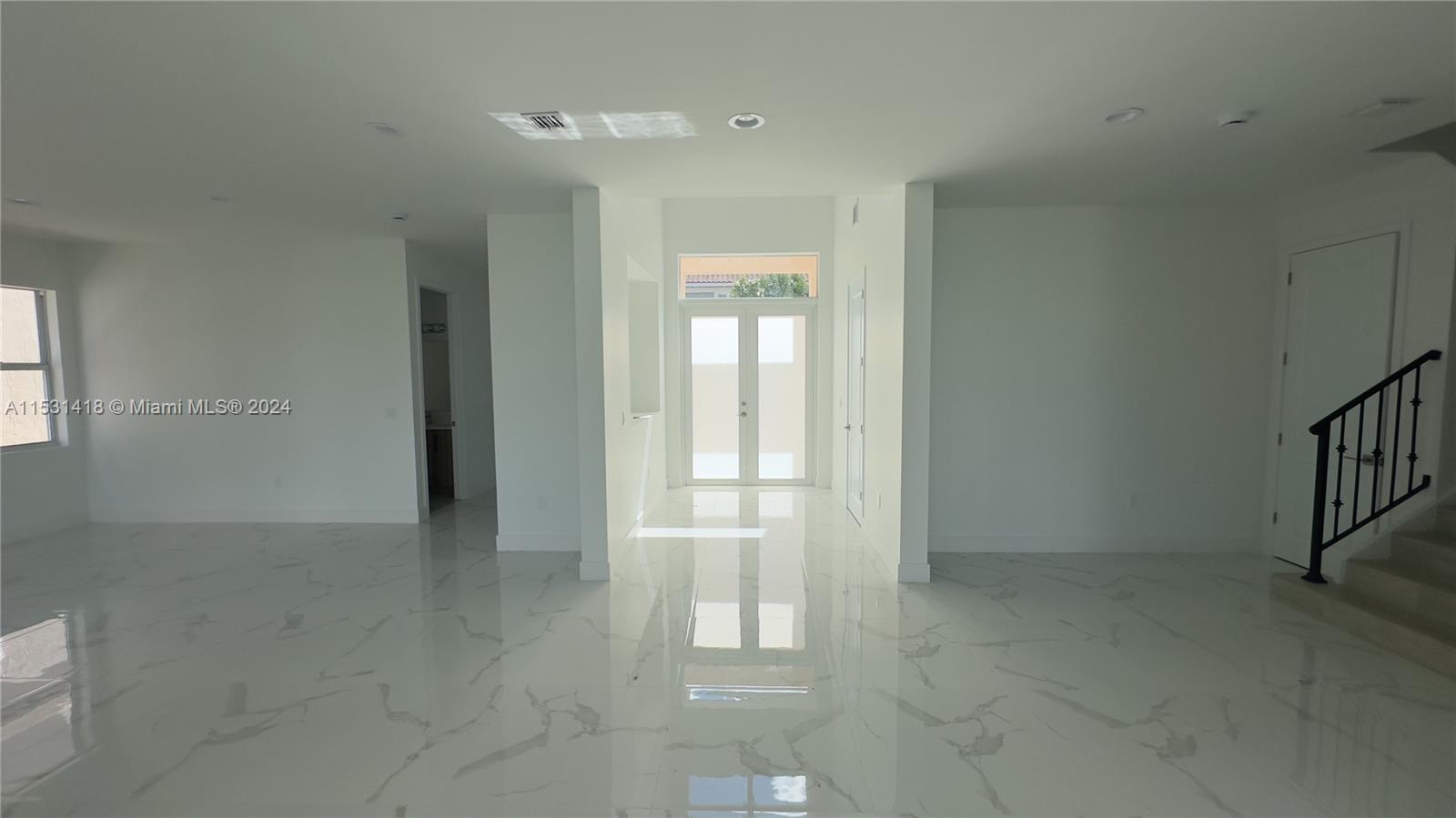 A bright, minimalist room features white marble-look tile flooring and a double-door entryway — 3523 Forest View Cir, Dania Beach FL 33312, DANIA BEACH, FL