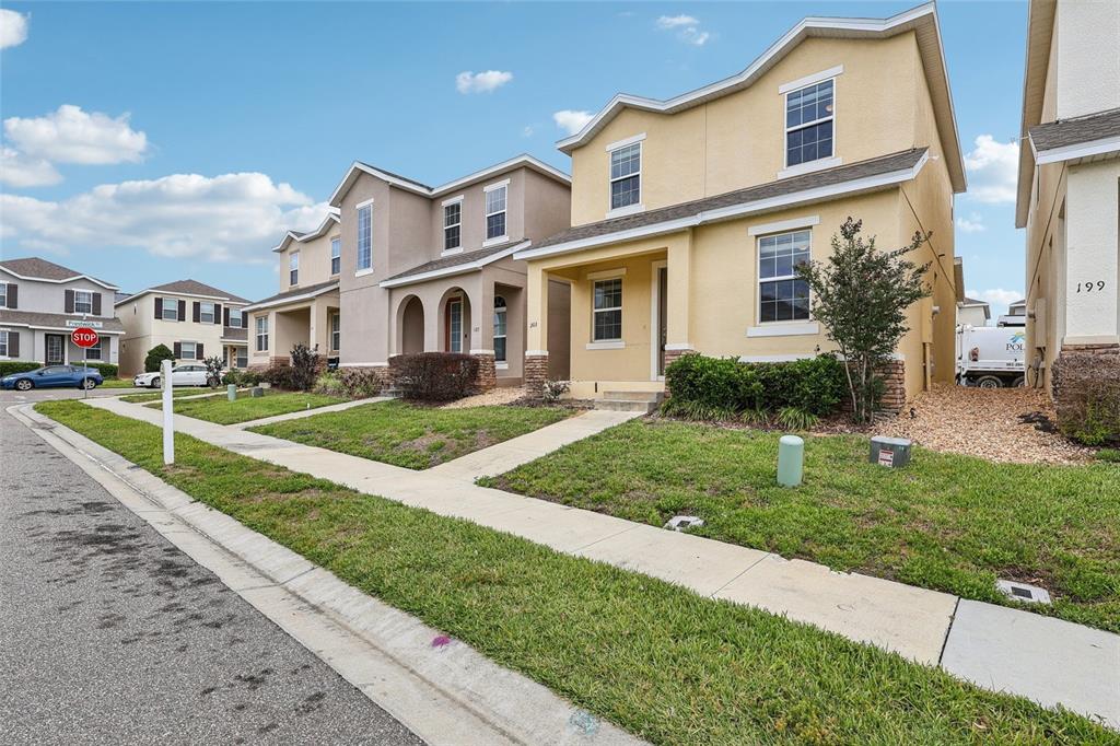 A row of suburban houses with yellow and tan stucco exteriors and front lawns — 203 BOYDFIELD LANE, DAVENPORT, FL