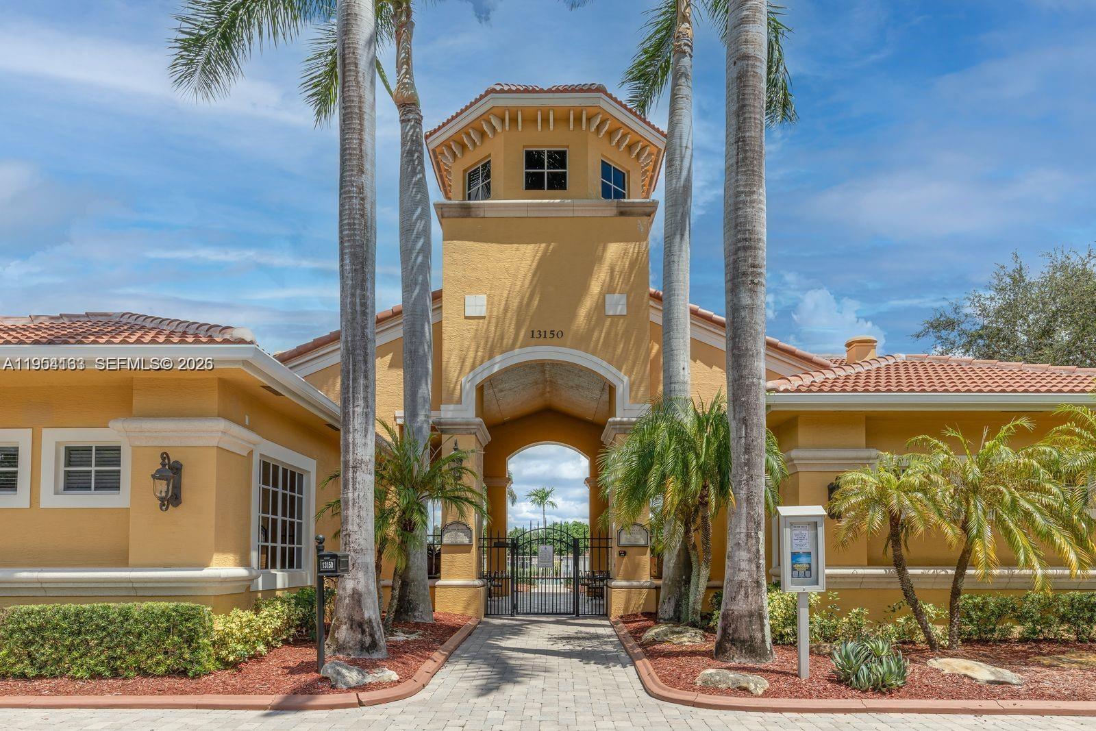 A yellow stucco building features a central tower with an arched entryway and palm trees — 13216 SW 44th St # 11204, Miramar FL 33027, MIRAMAR, FL