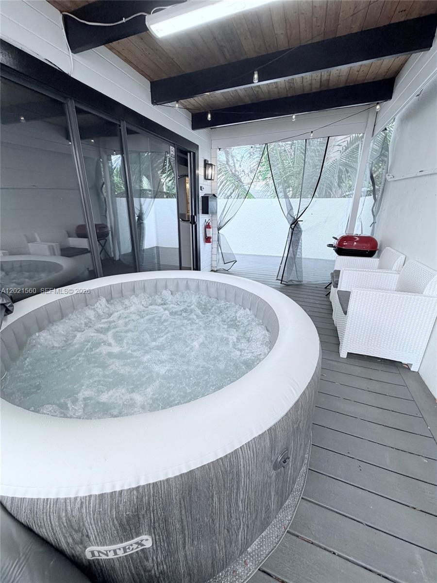 A covered deck features an inflatable hot tub, white wicker chairs, and a small grill — TAVERNIER, FL