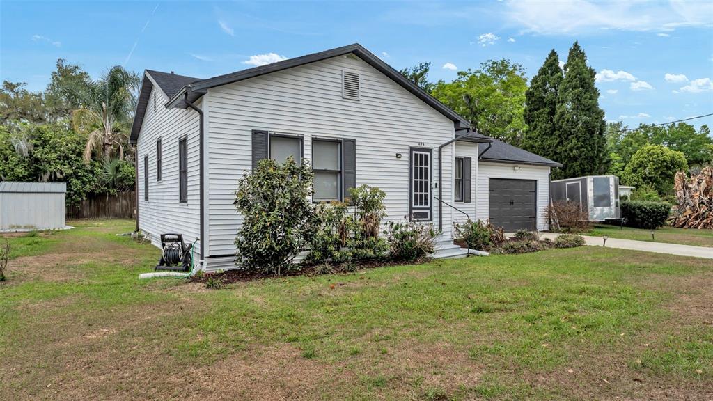 A single-story house with white vinyl siding, a dark roof, and an attached garage — 495 W PLUMOSA STREET, BARTOW, FL