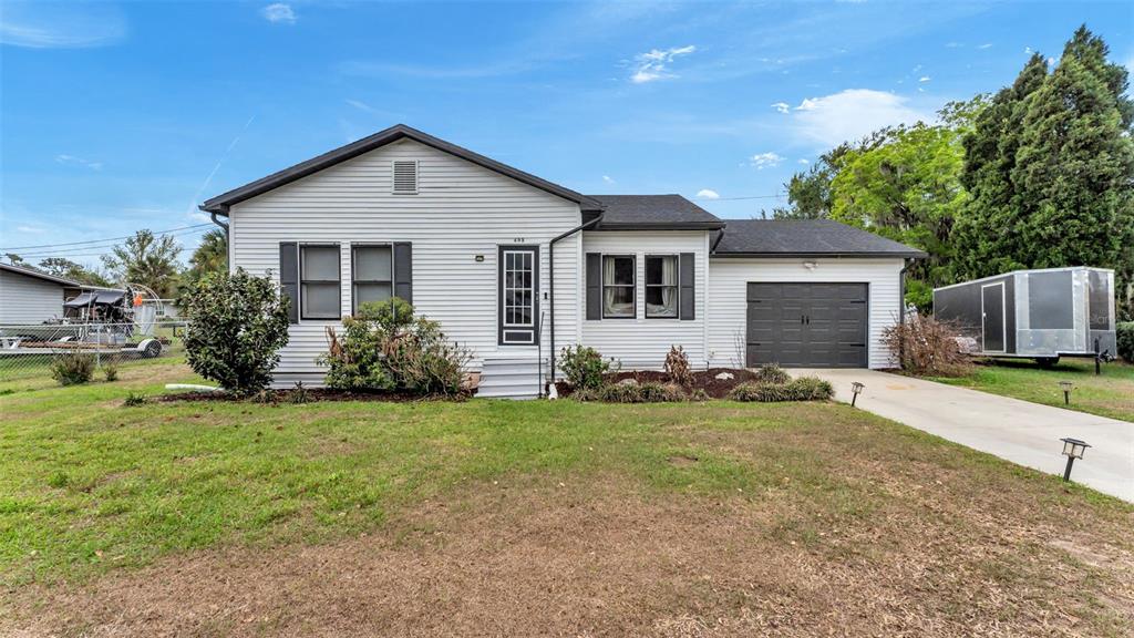 A single-story white house with a dark roof, garage, and a front lawn — 495 W PLUMOSA STREET, BARTOW, FL