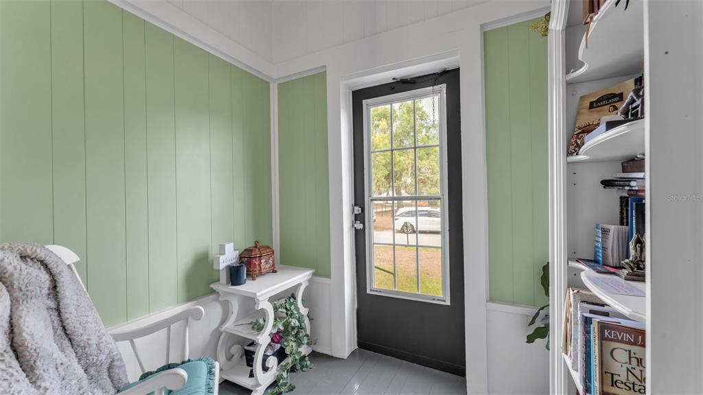 A sunroom with light green paneled walls, a white console table, and a glass-paneled door — 495 W PLUMOSA STREET, BARTOW, FL